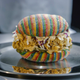 A chicken sandwich made of a fried chicken patty, cole slaw, and pickles on a rainbow bun made from Airheads candy